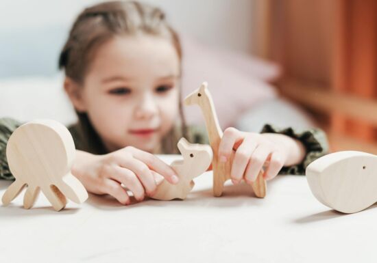 kleuter speelt met houten dierenfiguren