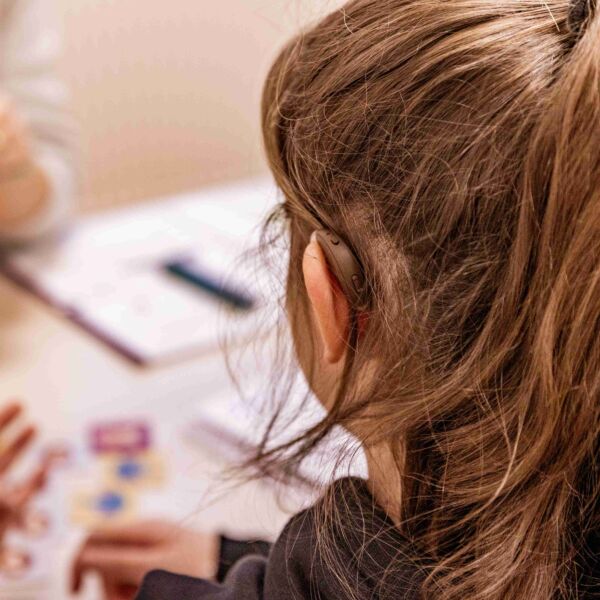 Meisje met lang donker haar en hoorapparaat krijgt begeleiding bij rekenoefening