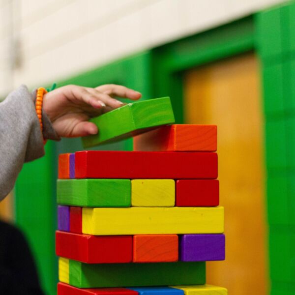 kinderhandje zet gekleurde blokken op een toren.