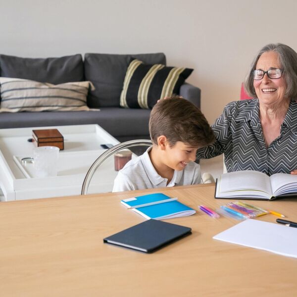 Oma met bril en grijze trui leest voor voor kind met witte trui