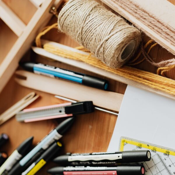 Verschillende materialen op een tafel. Pennen, touw, geodriehoek, breekmes, passer, houten latje, schrift, ...
