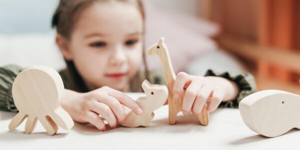 kleuter speelt met houten dierenfiguren