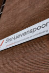 Rode bakstenen muur met benaming Sint-Lievenspoort, samen sterk in communicatie en ontwikkeling, met logo