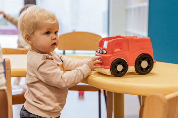 blonde peuter met rode speelgoedauto
